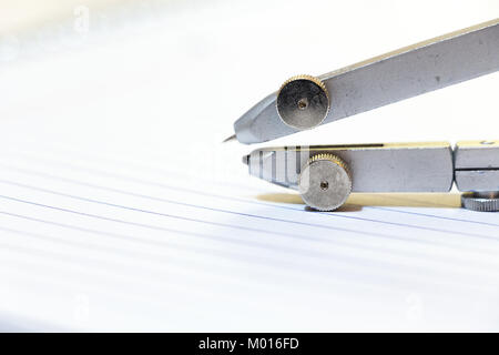 Details of a metal drawing - drafting compass on a sheet paper. Stock Photo