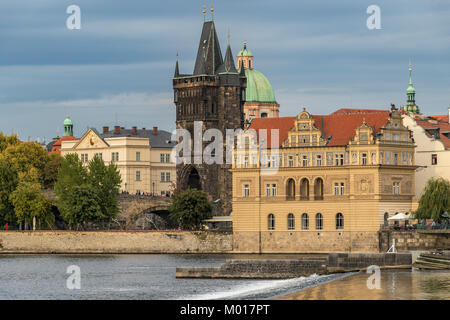 Prague Old Town and The Charles Bridge with the Old Town Bridge Tower viewed from The Banks Of The River Vlatava bathed in late afternoon sunlight Stock Photo