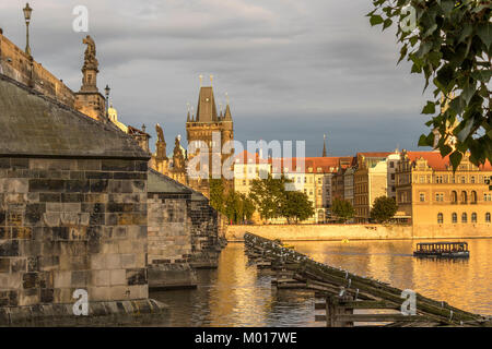 Prague Old Town and The Charles Bridge with the Old Town Bridge Tower viewed from The Banks Of The River Vlatava bathed in late afternoon sunlight Stock Photo
