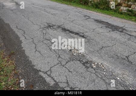 Damaged rural road, cracked asphalt blacktop with potholes ...