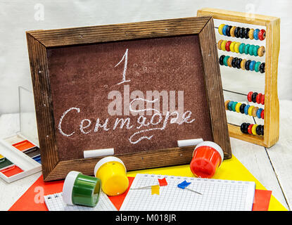 Day of knowledge. School board with the inscription on September 1, paints, colored paper, abacus and notebooks Stock Photo