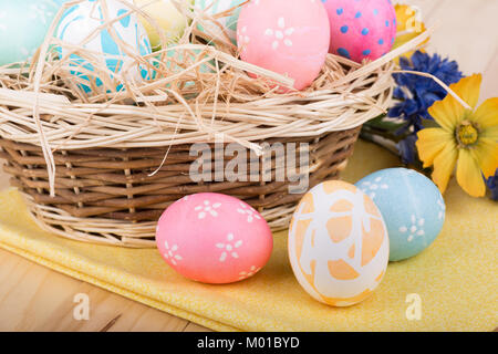 Three Easter eggs in front of a basket of eggs Stock Photo