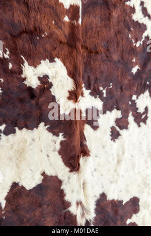 A close-up of a cowhide with natural brown and white fur pattern, showcasing the unique texture and organic design, Stock Photo