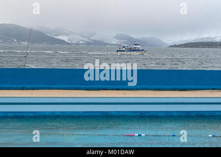 Gourock outdoor salt water heated swimming pool out of season, with ferry sailing across the Firth of Clyde behind, Gourock, Scotland, UK Stock Photo
