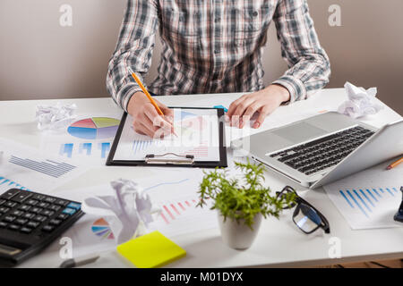 Businessman holding a pen is working with graph documents. Stock market chart and finger pointing on tablet in office. Stock Photo
