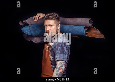 Artist working with leather working as artisan at the workplace./Leather Artist produces leather workpiece. Stock Photo