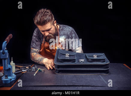 Leather Craftsman creates quality product of leather in the shop./Leather Currier working with leather using crafting tools at his place of work. Stock Photo