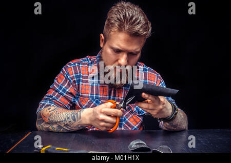 Leather cutter manufacturing new leather product./Craftsman working with leather creates a new leatherwork. Stock Photo