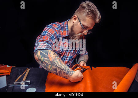 Leather Skinner keen on one's business./Leather Professional creating new leatherwork at workplace. Stock Photo