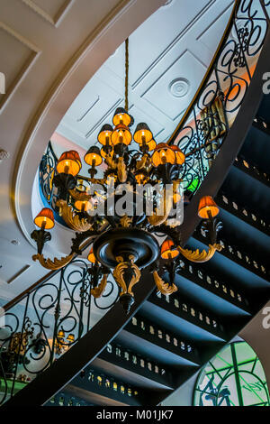 Architecture interior, candelabra and curved staircase viewed from below. Building interior detail, spiral staircase, ceiling and chandelier. Stock Photo