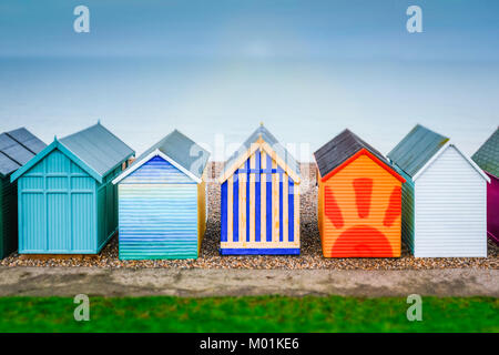 pretty painted colourful wooden beach huts with a tilt shift effect on a misty day at the seaside in Kent, Herne Bay UK Stock Photo