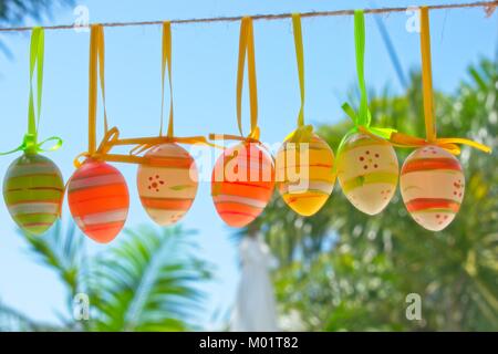 Easter decoration, colourful Easter eggs hanging on a rope in a tropical backyard. Stock Photo