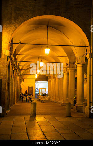 Cafes line a portico facing Piazza Grande at night in Modena Italy Stock Photo