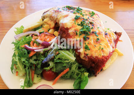Chicken Schnitzel with chips and fresh garden salad on timber background Stock Photo