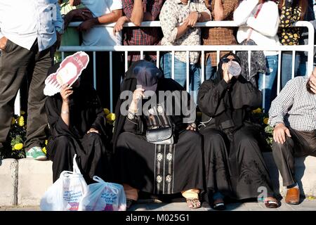 Burka clad women shield themselves from the Qatar sun. Stock Photo