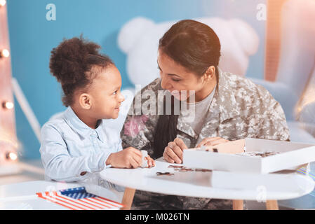 Joyful happy mother and daughter doing jigsaw puzzle Stock Photo