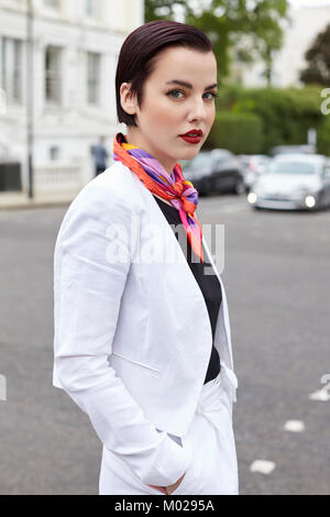 Woman standing in street wearing short white linen jacket Stock Photo