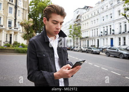 Young man standing in street using smartphone touchscreen Stock Photo