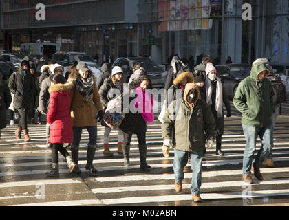 People bundled up on a cold winter day crossing 6th Avenue along 42nd Street at Bryant Park, in midtown Manhattan. Stock Photo