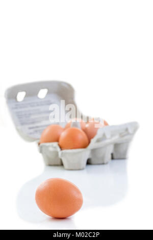 Close up shot of an open recyclable egg carton with 5 eggs inside and one egg next to it on a white background Ecological healthy food from bio farms. Stock Photo