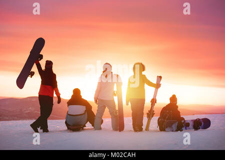 Happy friends at ski resort against sunset Stock Photo