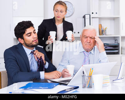 Mature man is having complicated issue with reports made by subordinates in office. Stock Photo