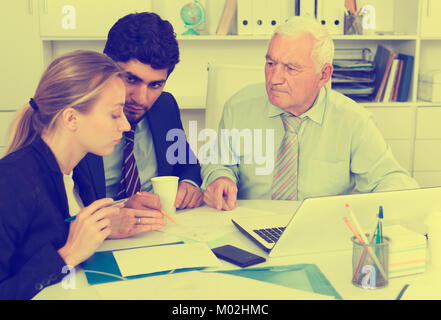 Managers are writing financial reports and discussing with mature boss in the office. Stock Photo