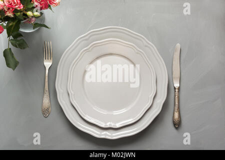 Festive table setting with flowers, vintage dishware, silverware and decorations on gray table. Top view. Concept. Stock Photo