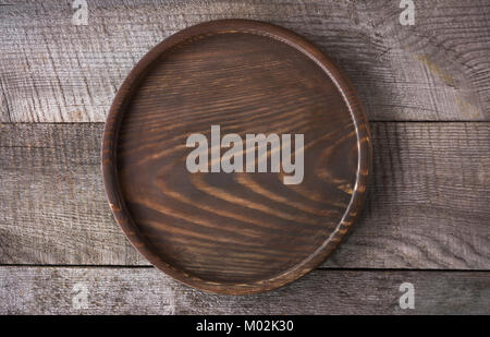 Brown round salver on wooden background. Brown round salver on wooden background. Brown round salver on board. Stock Photo