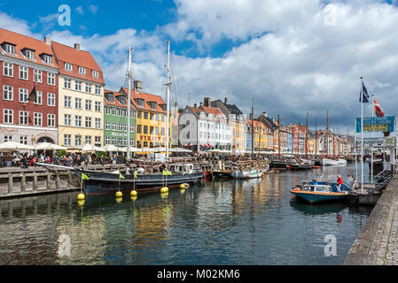 View of Nyhavn in Copenhagen Denmark UK looking towards the harbour entrance with canal boat taking on passengers for a harbour cruise Stock Photo