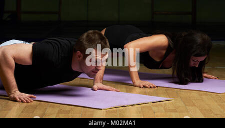 Man and woman doing push ups in gym background close-up Stock Photo