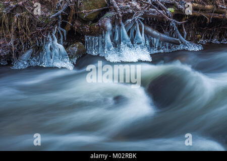 Icicles and water flow of the river Stock Photo