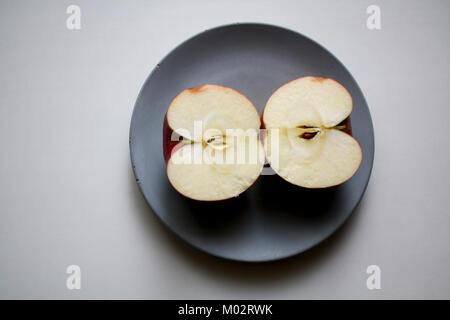 Two red apple halves isolated on grey concrete plate from above Stock Photo
