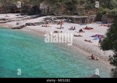 CORFU, GREECE - MAY 31, 2016: People enjoy the beach in Kassiopi, Corfu Island, Greece. 558,000 tourists visited Corfu in 2012. Stock Photo