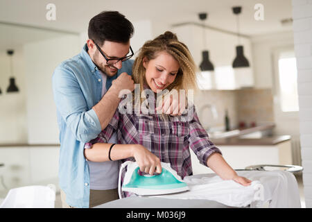 Young couple at home doing hosehold chores and ironing Stock Photo