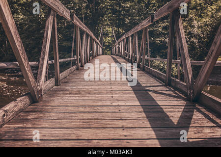 A straight wooden bridge path, showcasing a simple and functional design. The path, built with sturdy wooden beams, is used for crossing a waterway or traversing natural terrain. Stock Photo