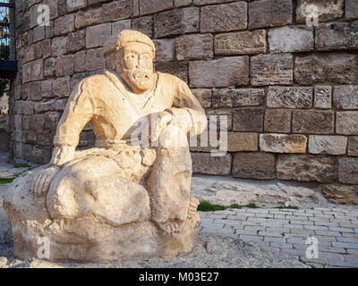 Ancient sculpture of a man at the foot of the Maiden Tower in Old Town in Baku, Azerbaijan. Stock Photo