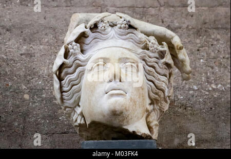 Head - Fragment of roman statue - god from ancient Corinth Greece with flowers or grapes in wavy hair and part of a hand Stock Photo