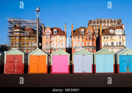 Brighton seafront 7 multi beach huts, behind is blue sky and three very ornate victorian buildings one of the buildings has scaffolding on it, infront Stock Photo