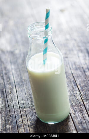 Bottle milk with straw on old wooden table. Stock Photo
