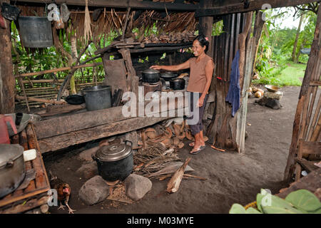 A Filipino woman cooks a meal over open flame in her outdoor 'dirty' kitchen near Legazpi City, Southern Luzon, Philippines. Stock Photo