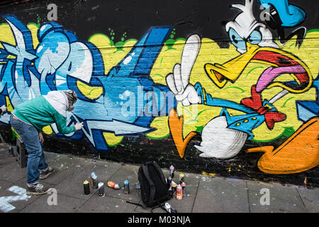 Brick Lane, East London is a creative zone for artists. This images records graffiti artists finishing off a piece of art. Stock Photo