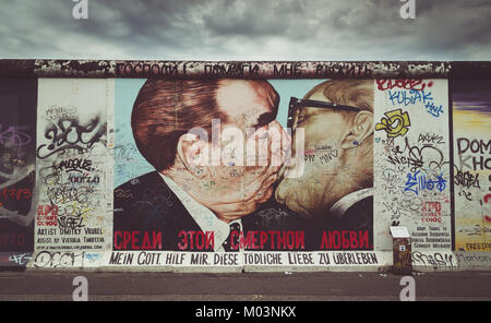 Street art graffiti painting 'The Kiss' by Dmitri Vrubel at famous East Side Gallery with retro vintage Instagram style filter effect, Berlin, Germany