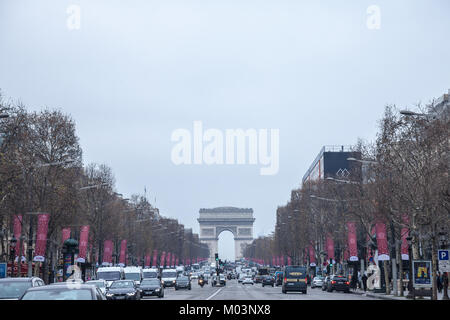 PARIS, FRANCE - DECEMBER 20, 2017: Champs Elysees avenue with the Arc de Triomphe in background during a cloudy foggy polluted day , with a traffic ja