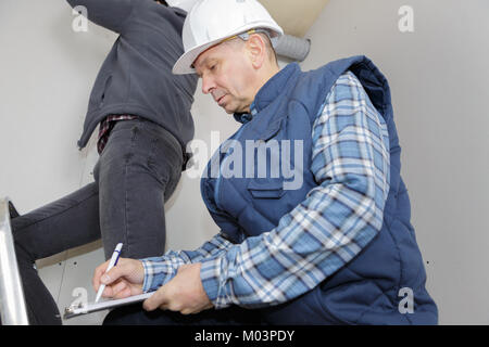 construction manager writing on a clipboard Stock Photo