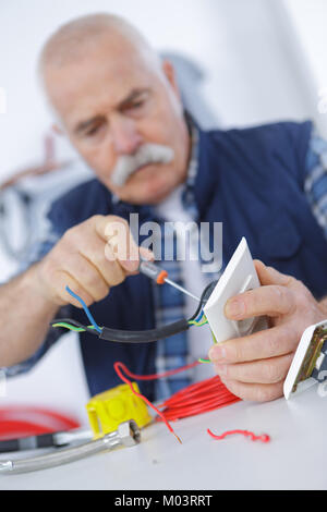 senior adult electrician checking and repairing plug Stock Photo