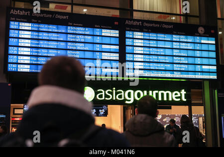 Berlin, Germany. 18th Jan, 2018. Passengers look at an electronic board displaying information of short-distance trains at the Berlin Central Train Station in Berlin, capital of Germany, on Jan. 18, 2018. All long-distance trains in Germany have been cancelled and at least three people were killed as a result of the storm 'Friederike', the German Press Agency (DPA) updated. Credit: Shan Yuqi/Xinhua/Alamy Live News Stock Photo