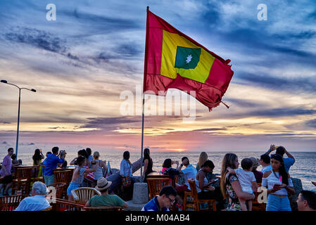 waving flag of Cartagena at sunset at Cafe del Mar Stock Photo