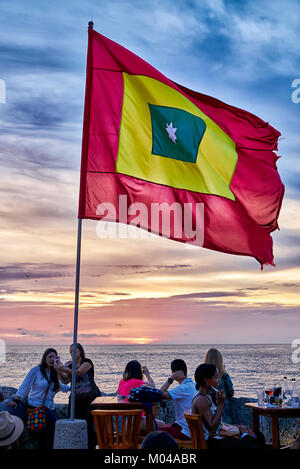 waving flag of Cartagena at sunset at Cafe del Mar Stock Photo