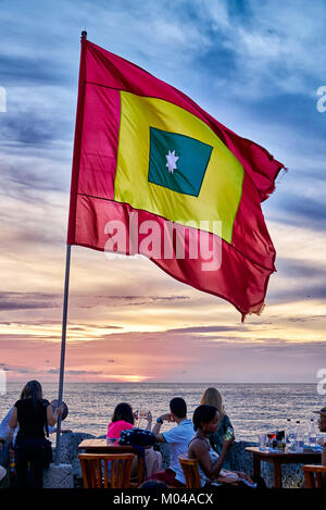waving flag of Cartagena at sunset at Cafe del Mar Stock Photo